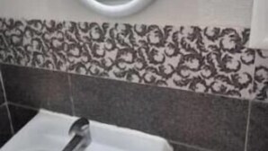 A bathroom with a white sink, a round mirror, and patterned tiles on the wall. - Your haven of peace with a sea view, a stone's throw from the city center (Hammamet)