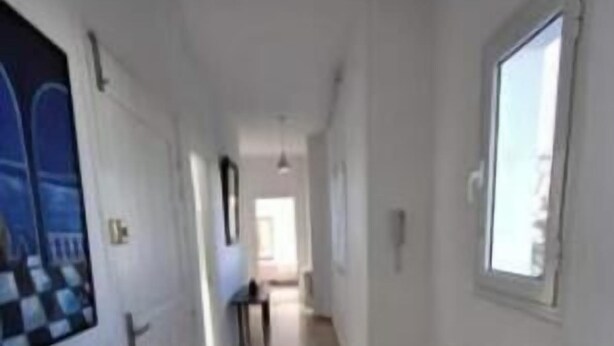 A narrow hallway with a radiator, a window, and a door on the right. - Your haven of peace with a sea view, a stone's throw from the city center (Hammamet)