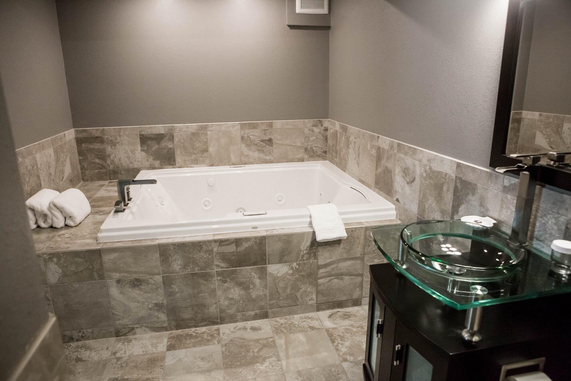 A modern bathroom with a rectangular bathtub, marble walls, and a glass sink.