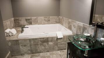 A modern bathroom with a rectangular bathtub, marble walls, and a glass sink.