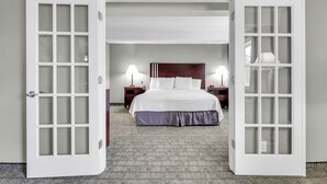 A hotel room with a large bed, two bedside lamps, a wooden headboard, and a carpeted floor. - Red Lion Inn & Suites Urbana (Urbana)