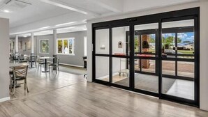 A spacious indoor area with a dining area, large sliding glass doors leading outside, and a visible brick fireplace. - Red Lion Inn & Suites Urbana (Urbana)