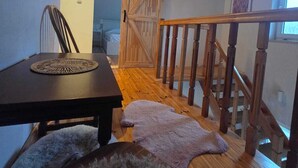 Un escalier en bois avec une rampe, une table à manger avec un set de table et un tapis moelleux sur le sol.