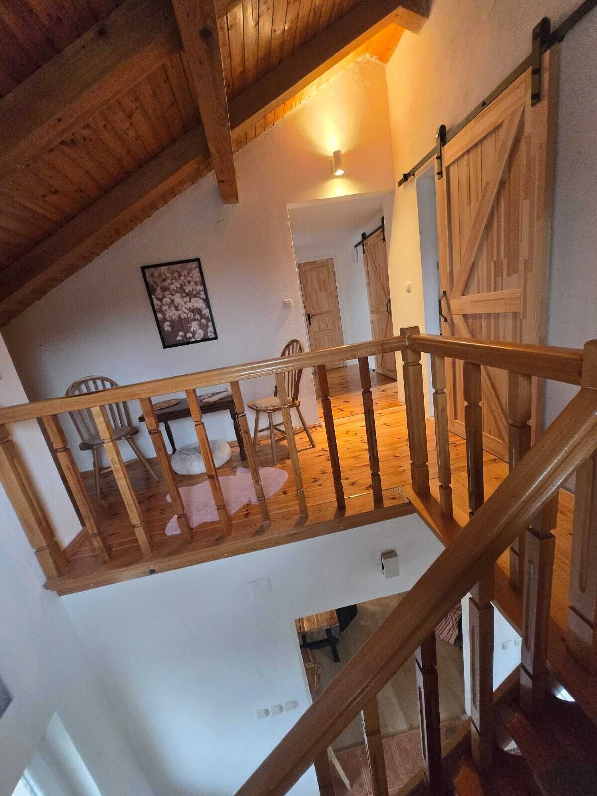 Un escalier en bois mène à un espace repas comprenant des chaises et une table.