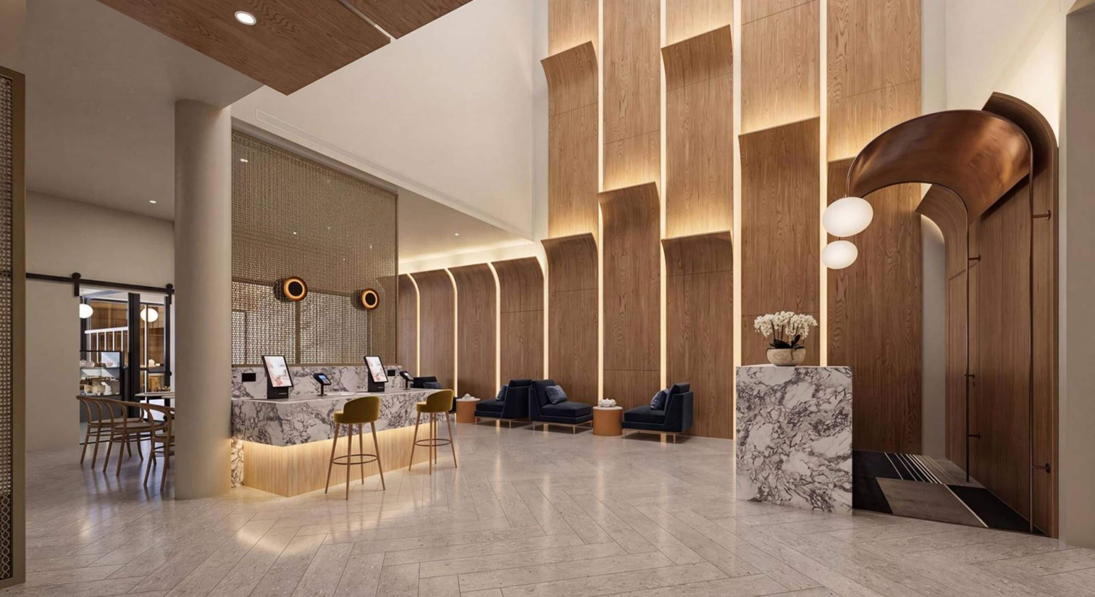 A modern lobby with a reception desk, seating area, and a decorative wall with vertical wooden panels.
