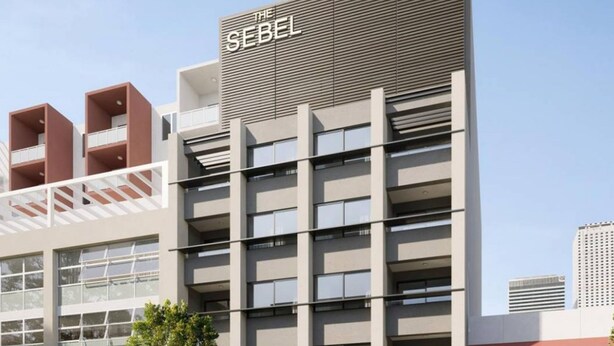Een modern gebouw met een opvallend bord waarop 'THE SEBEL' staat.