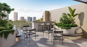 Eine Dachterrasse mit Sitzgelegenheiten im Freien, Pflanzen und Blick auf die Stadt.