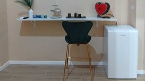 A kitchen with a white refrigerator, a green chair, a white shelf with kitchen items, and a red heart-shaped decoration. - Antonella's Suites (Taranto)