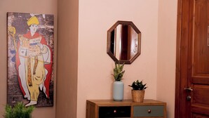 A wooden cabinet with drawers, a mirror, a vase with flowers, and a framed picture on the wall. - Napolicentrico (Naples)