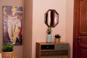 A wooden cabinet with drawers, a mirror, a vase with flowers, and a framed picture on the wall. - Napolicentrico (Naples)