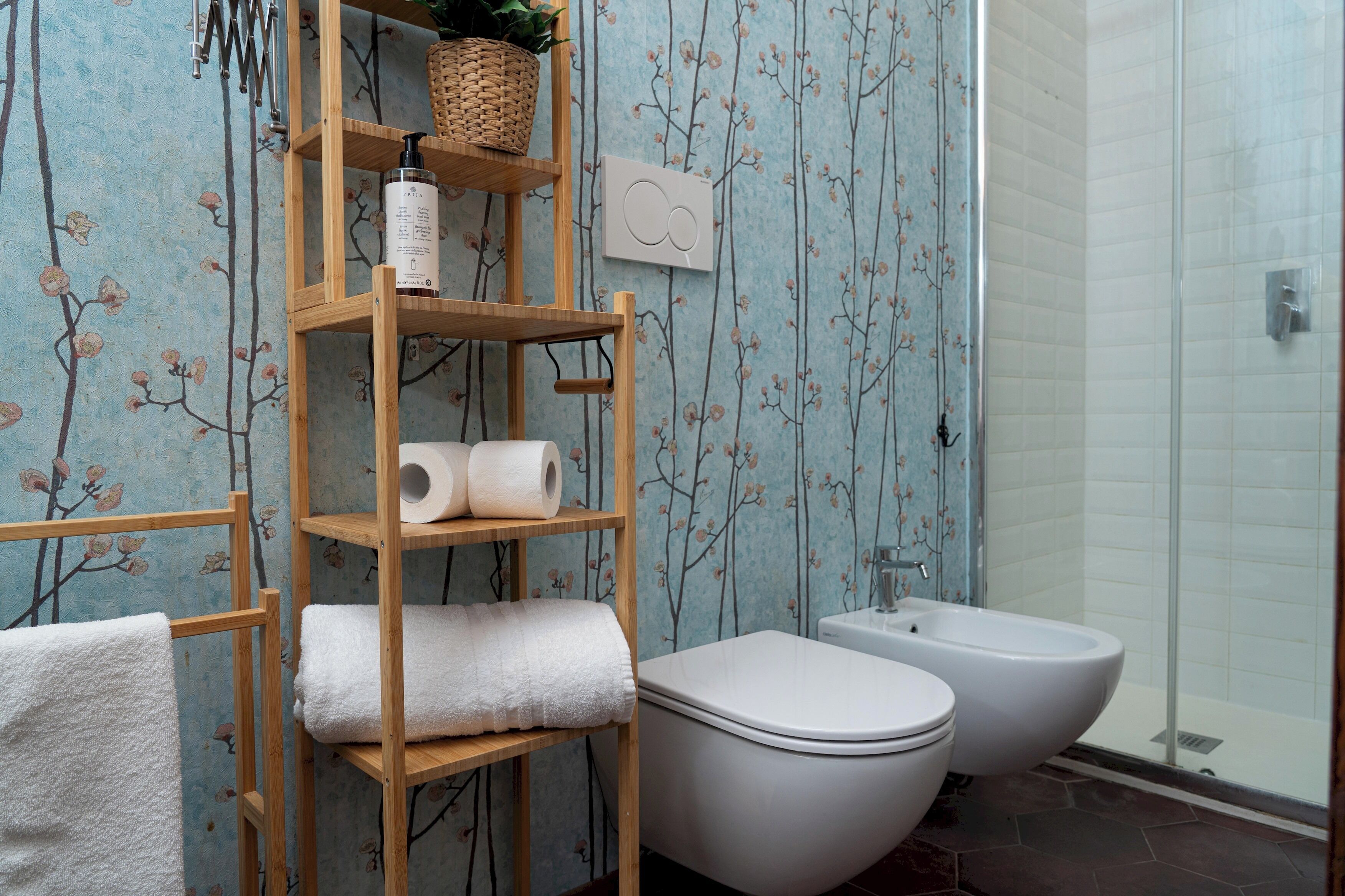 Ein Badezimmer mit Toilette, Bidet, einer Holzablage mit Handtüchern und einer Duschkabine.