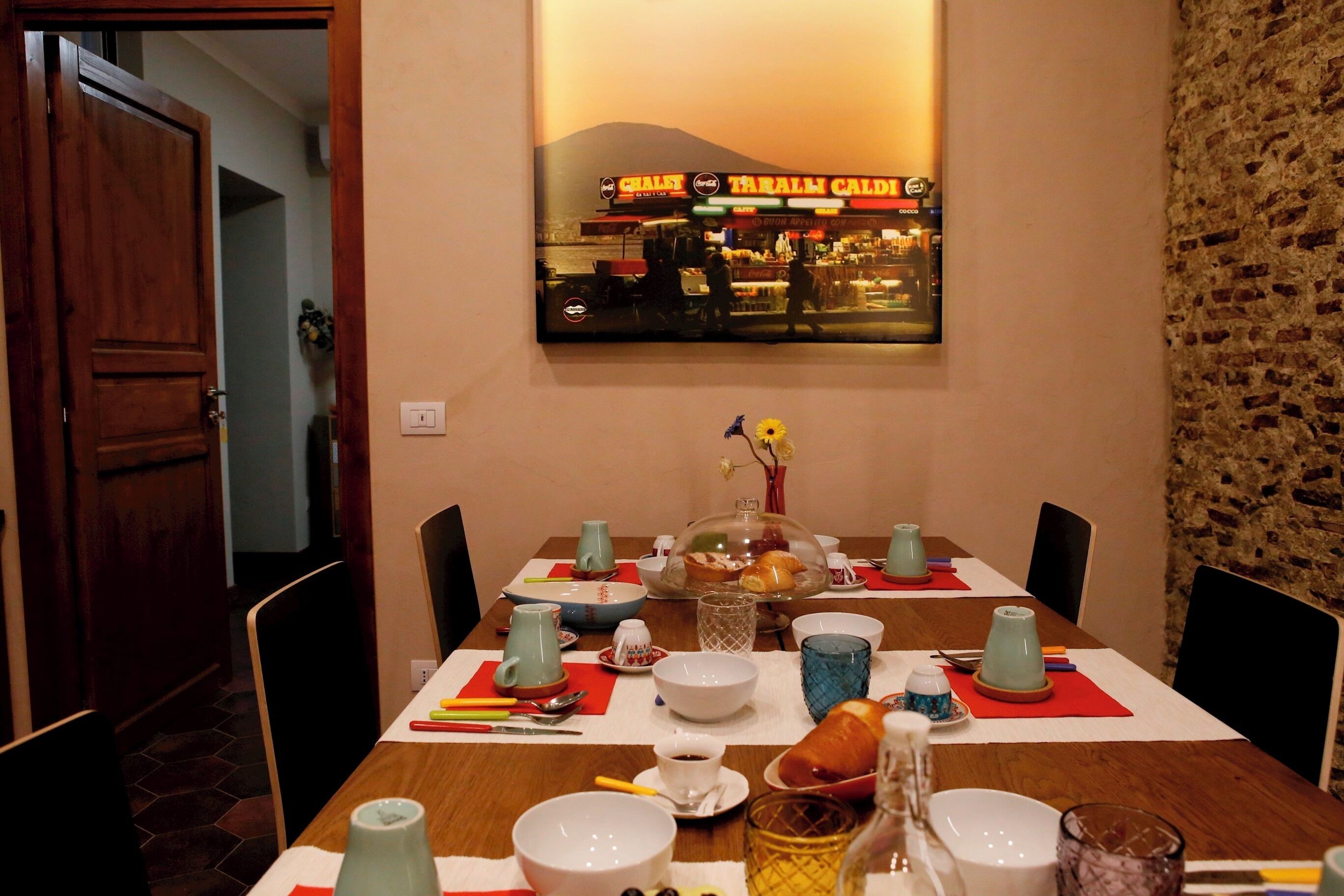 A dining table set with various dishes, glasses, and a bread basket, with a cityscape view in the background.