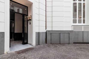 A building entrance with a black door, a letter 'B' sign, and a stone-paved courtyard. - Casa di Andrea (Naples)