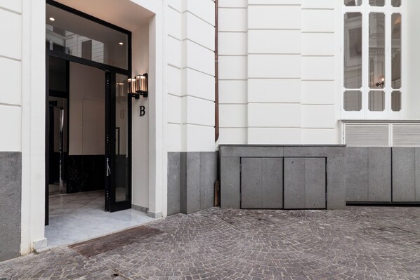 A building entrance with a black door, a letter 'B' sign, and a stone-paved courtyard. - Casa di Andrea (Naples)