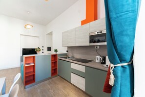A modern kitchen with grey cabinets, a black countertop, and a built-in oven. - Casa di Andrea (Naples)