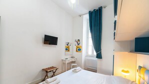 A hotel room with a bed, a desk, a chair, a TV, and artwork on the wall. - Casa di Andrea (Naples)