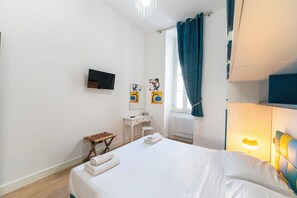 A hotel room with a bed, a desk, a chair, a TV, and artwork on the wall. - Casa di Andrea (Naples)