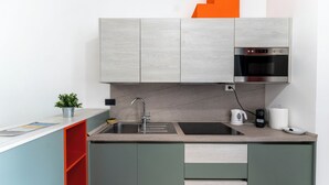 A modern kitchen with grey cabinets, a black sink, and a built-in oven. - Casa di Andrea (Naples)