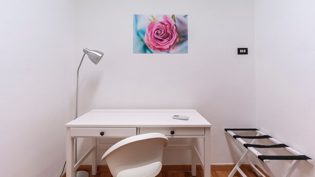 Een wit bureau met een lamp, een stoel en een zwart-wit bankje.