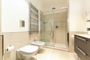 A modern bathroom with a glass-enclosed shower, two sinks, and a vanity with a mirror. - Casa di Rosy (Naples)