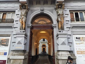 A grand entrance with two statues on either side, an ornate archway, and a sign for a business office. - Casa di Rosy (Naples)