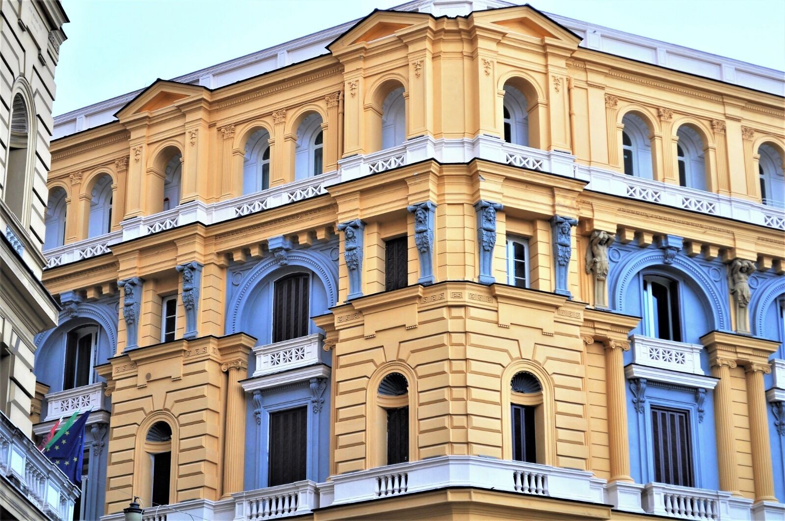 A corner building with classical architecture, featuring multiple arched windows and decorative moldings.