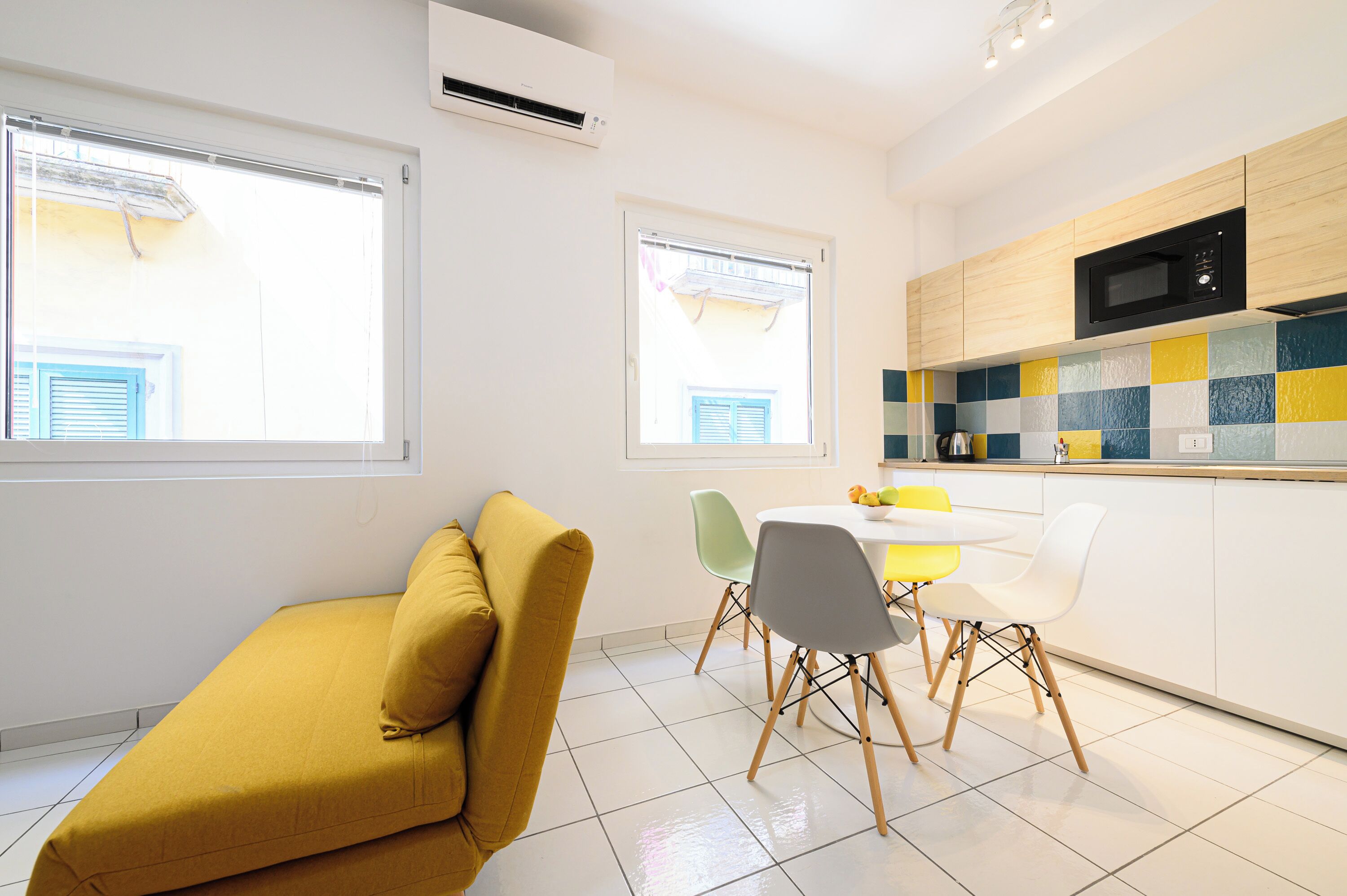 Eine moderne Küche mit Mikrowelle, ein Essbereich mit Stühlen und ein Sofa.