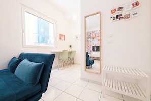 A modern room with a blue sofa, a desk, and a mirror. - L'Aurora Apartments (Naples)