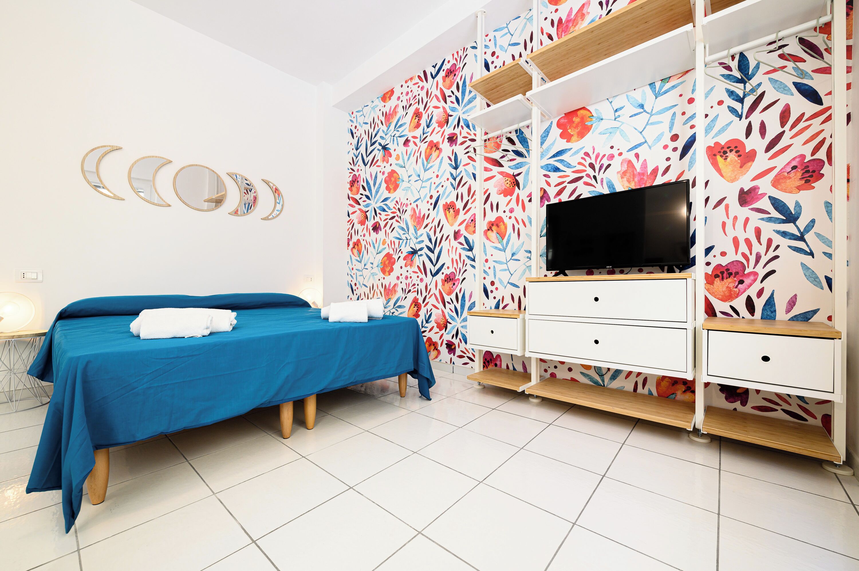 A bedroom with a bed, a TV, and a white dresser.