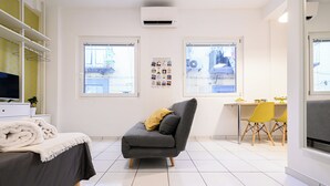 A modern room with a grey sofa, a dining table with yellow chairs, and a TV on a white cabinet. - L'Aurora Apartments (Naples)