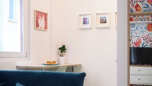 A room with a desk, a potted plant, a small table with a glass and a plate, and a blue chair. - L'Aurora Apartments (Naples)