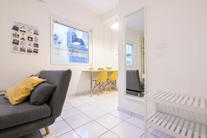 A modern living room with a grey sofa, yellow cushions, a dining area with yellow chairs, and a white radiator. - L'Aurora Apartments (Naples)