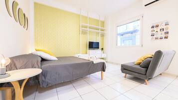 A modern bedroom with a bed, bedside table, chair, and a TV.