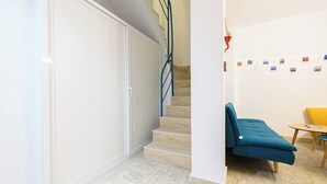 A modern interior with a staircase, a blue sofa, and a small table. - L'Aurora Apartments (Naples)