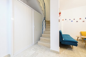 A modern interior with a staircase, a blue sofa, and a small table. - L'Aurora Apartments (Naples)