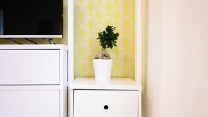 A white bedside table with a potted plant and a television on a stand. - L'Aurora Apartments (Naples)