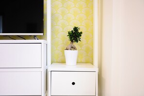 A white bedside table with a potted plant and a television on a stand. - L'Aurora Apartments (Naples)