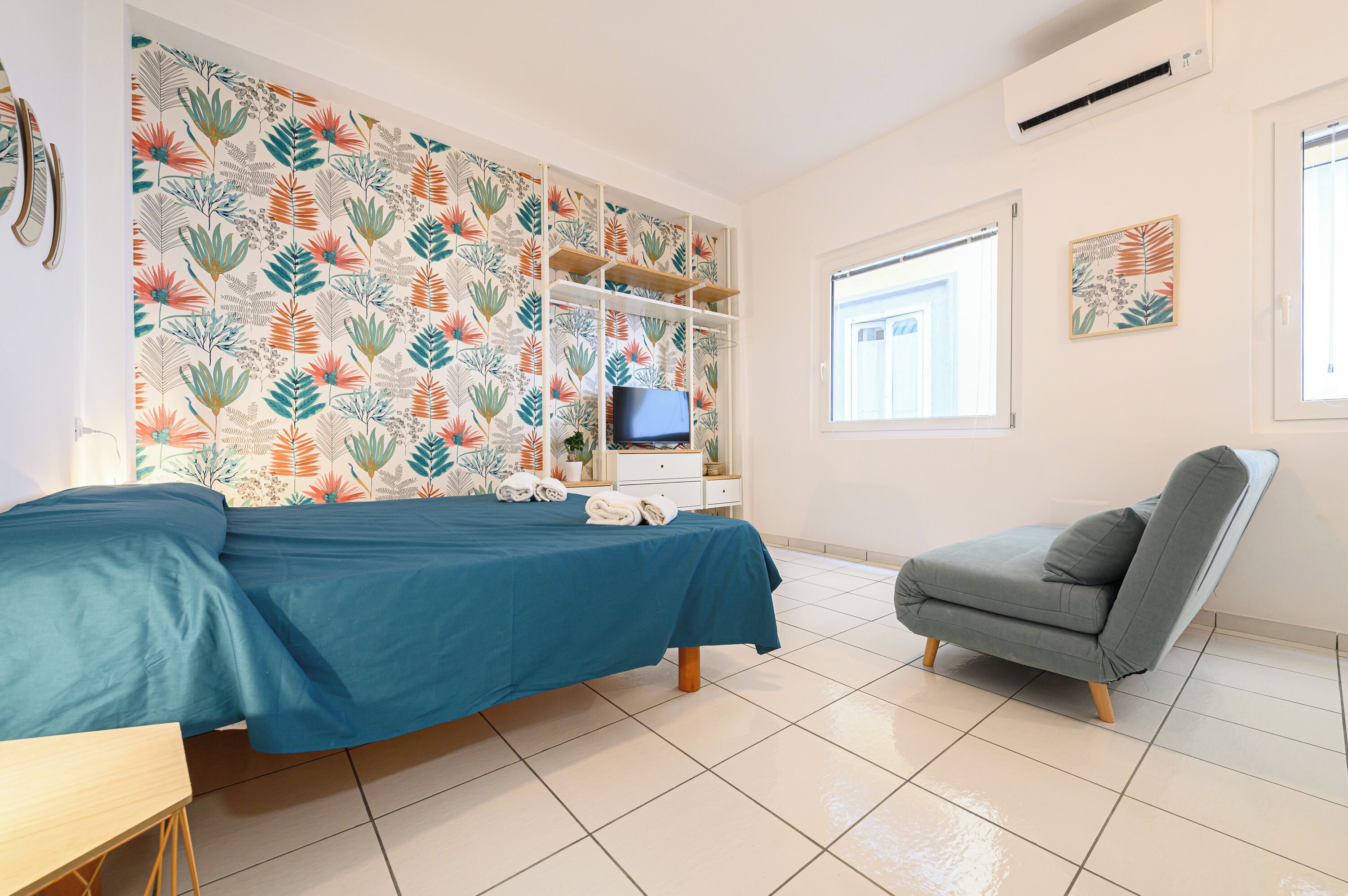 Een slaapkamer met een bed, een stoel, een televisie en een raam.