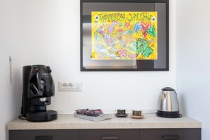 A kitchen counter with a coffee maker, a kettle, and a framed colorful artwork. - Via Galiani 20 (Naples)