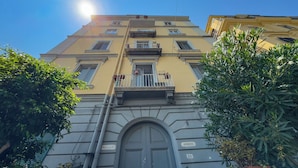 A multi-story building with a central entrance, balconies, and a clear sky. - Via Galiani 20 (Naples)