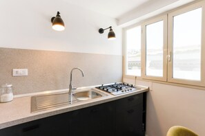 Eine moderne Küche mit Gasherd, Edelstahl-Spüle und zwei Wandleuchten.