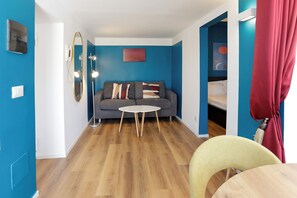 A modern living room with a grey sofa, a round white table, and a blue accent wall. - Via Galiani 20 (Naples)