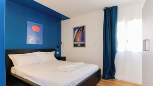 A hotel room with a bed, a nightstand, a poster on the wall, and a window with curtains. - Via Galiani 20 (Naples)