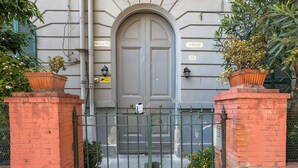 Un edificio con una amplia entrada arqueada, una reja metálica y macetas con plantas a ambos lados.