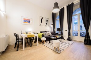 A modern living room with a sofa, dining table, chairs, and artwork on the walls. - Apt503a (Naples)
