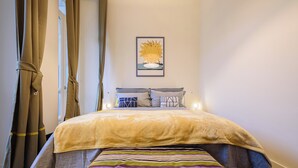 Ein ordentlich bezogenes Bett mit einer gestreiften Decke, einem Kissen auf dem Kopfteil und einem gerahmten Bild an der Wand.