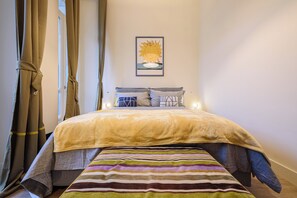 Ein ordentlich bezogenes Bett mit einer gestreiften Decke, einem Kissen auf dem Kopfteil und einem gerahmten Bild an der Wand.