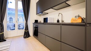Eine moderne Küche mit dunklen Schränken, einem eingebauten Backofen und einem Fenster mit Vorhängen.