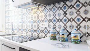 Eine Küche im modernen Design mit ornamental gestalteter Spritzschutzwand, einer Edelstahl-Spüle und einer Arbeitsplatte mit Küchengeräten.