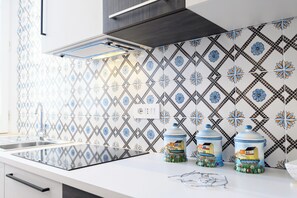 A kitchen with a modern design, featuring a patterned backsplash, a stainless steel sink, and a countertop with kitchen appliances. - Corso Umberto 58 (Naples)